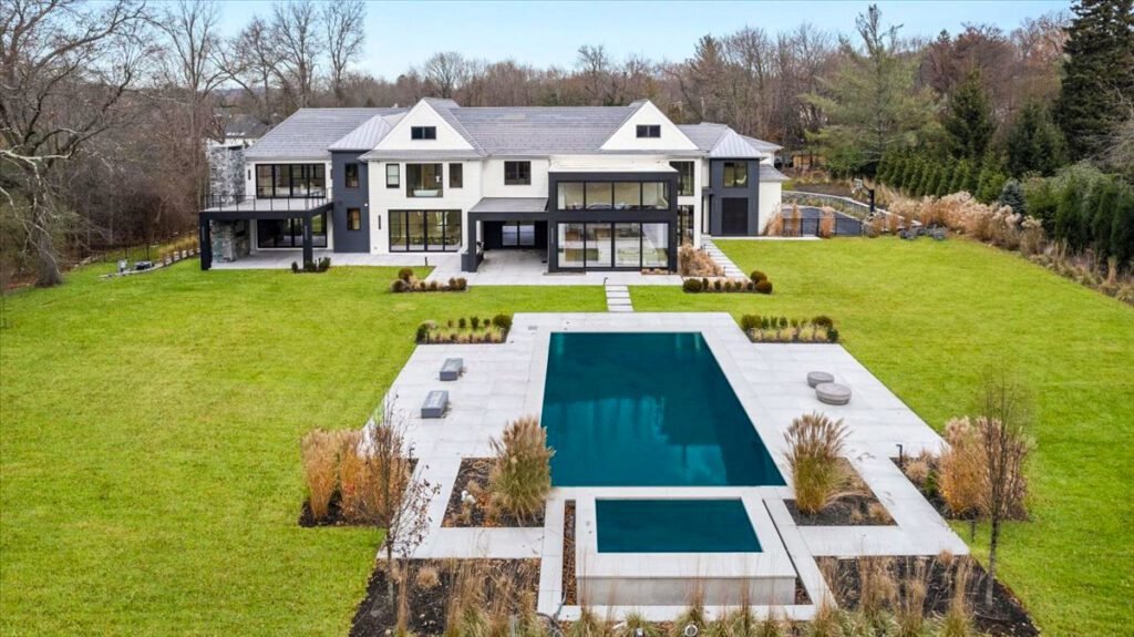 modern, luxury two-story home featuring large, black-framed European-style windows and sleek entry doors. The architectural design emphasizes symmetry, clean lines, and ample natural light through expansive glass surfaces. The windows are likely energy-efficient and custom-fitted, enhancing both curb appeal and performance. The front door and secondary entry doors appear to be minimalist and well-integrated into the overall design.
