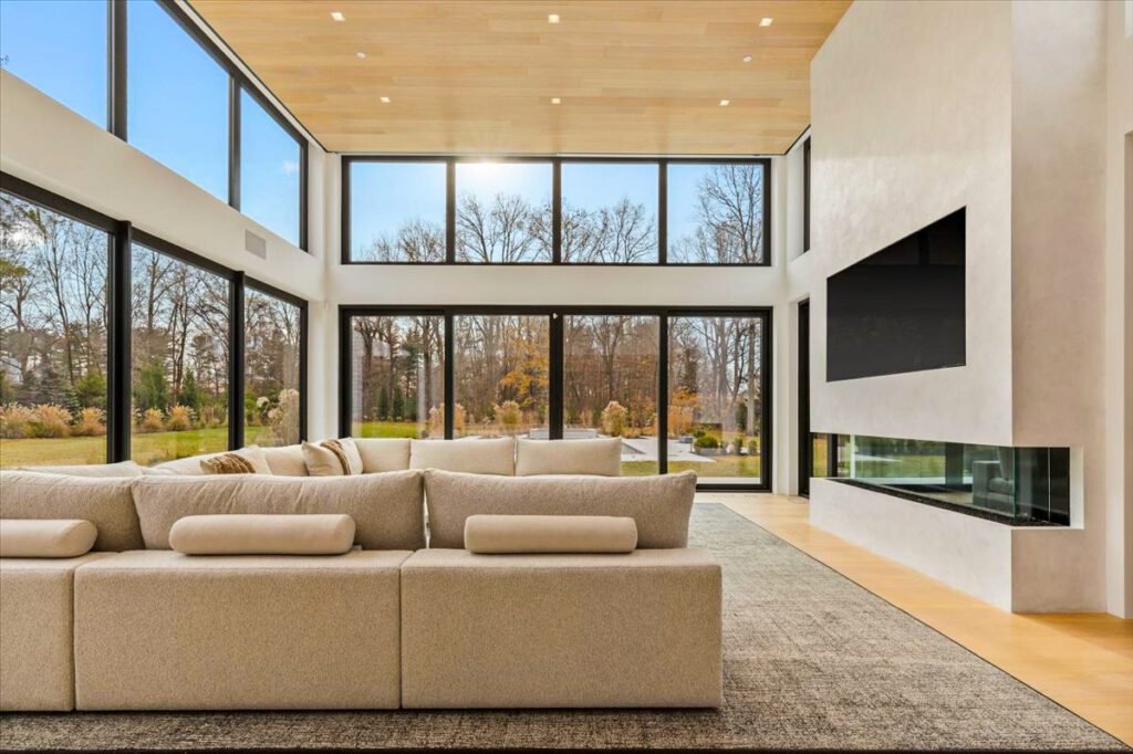 A spacious, elegant living room with large black-framed European windows and a modern patio door. The installation provides abundant natural light and seamless indoor-outdoor flow. The high-performance glass enhances energy efficiency while adding a luxurious architectural element.