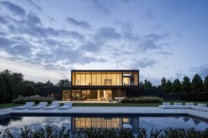 A modern two-story home with expansive European tilt-and-turn aluminum windows, featuring clean white framing, natural wood accents, and floor-to-ceiling glass integrated into a minimalist architectural design.